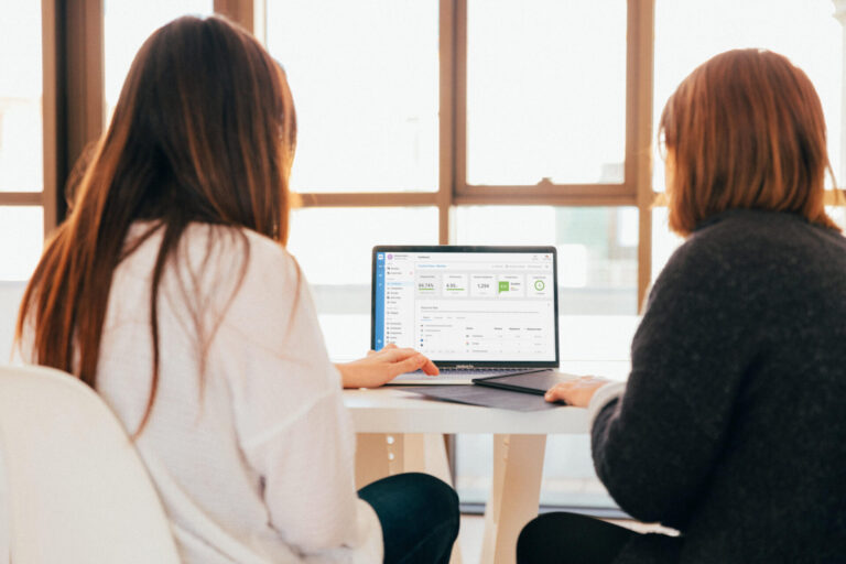 A picture featuring 2 ladies looking at a screen laptop featuring the TrustYou Review Dashboard.